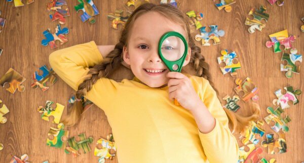 Girl with magnifying glass solving a puzzle
