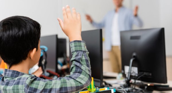 student raising his hand in a computer class