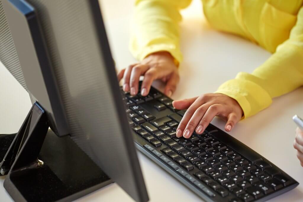 Woman writing code on desktop computer
